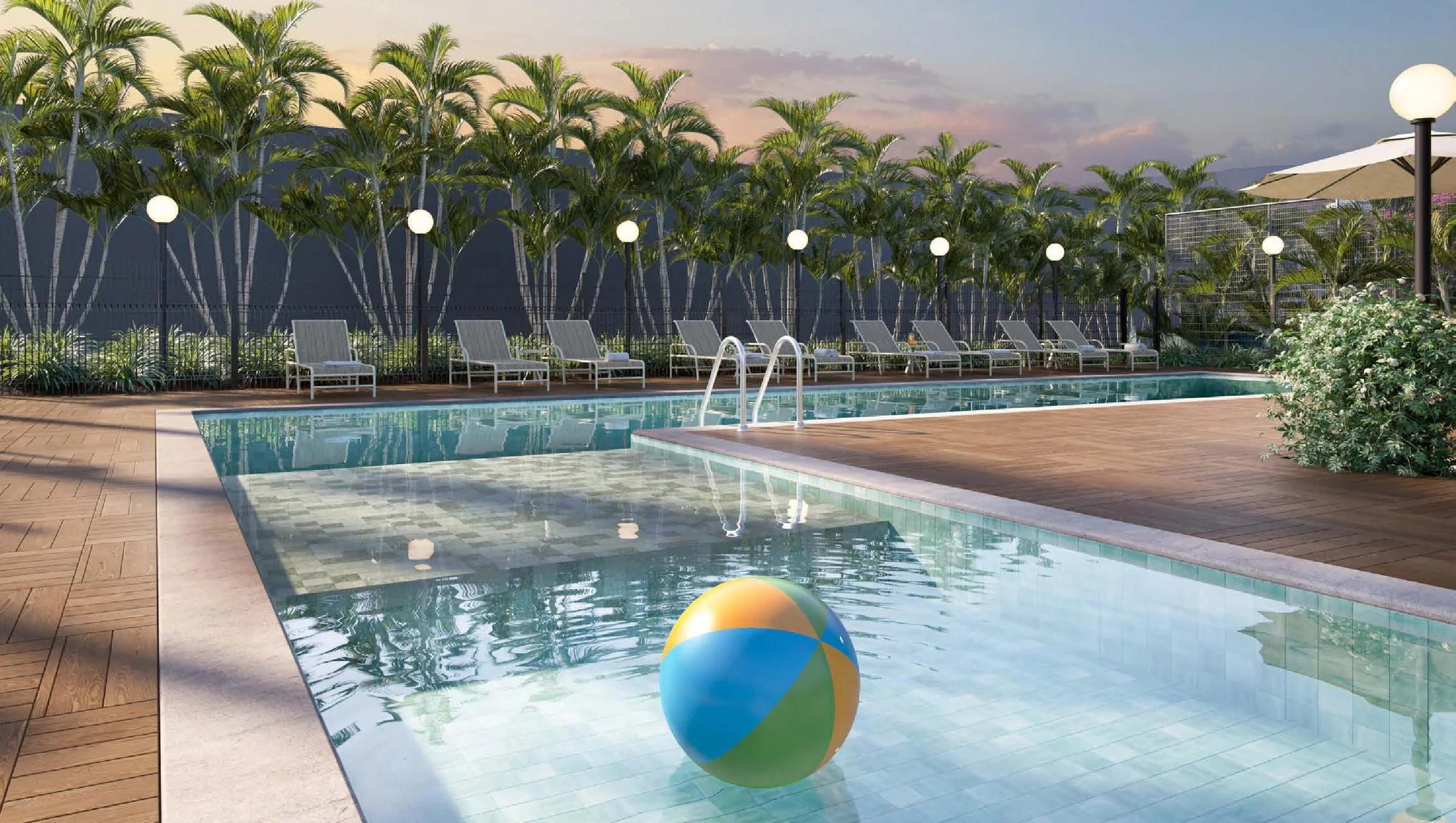 Piscina com área rasa de prainha e deck molhado cercada por palmeiras