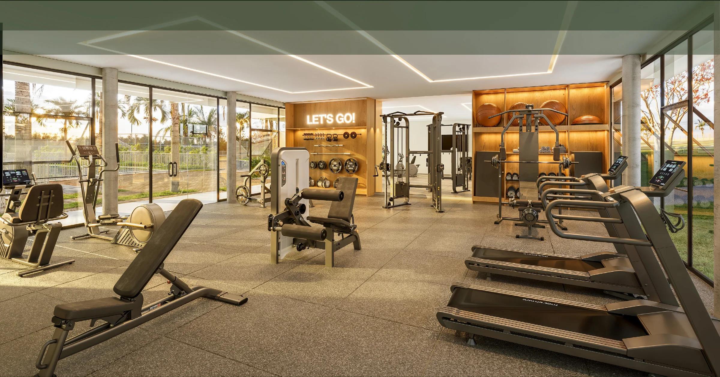 Academia equipada com esteiras, aparelhos de musculação e vista para o jardim