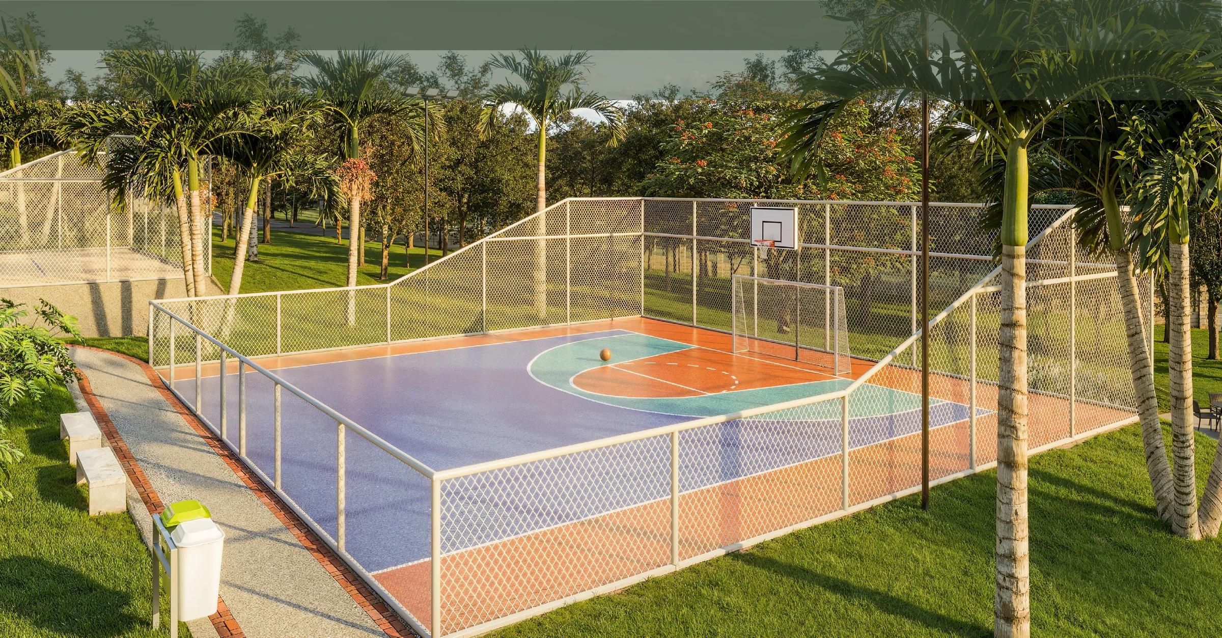 Quadra poliesportiva cercada com alambrado, tabela de basquete e traves