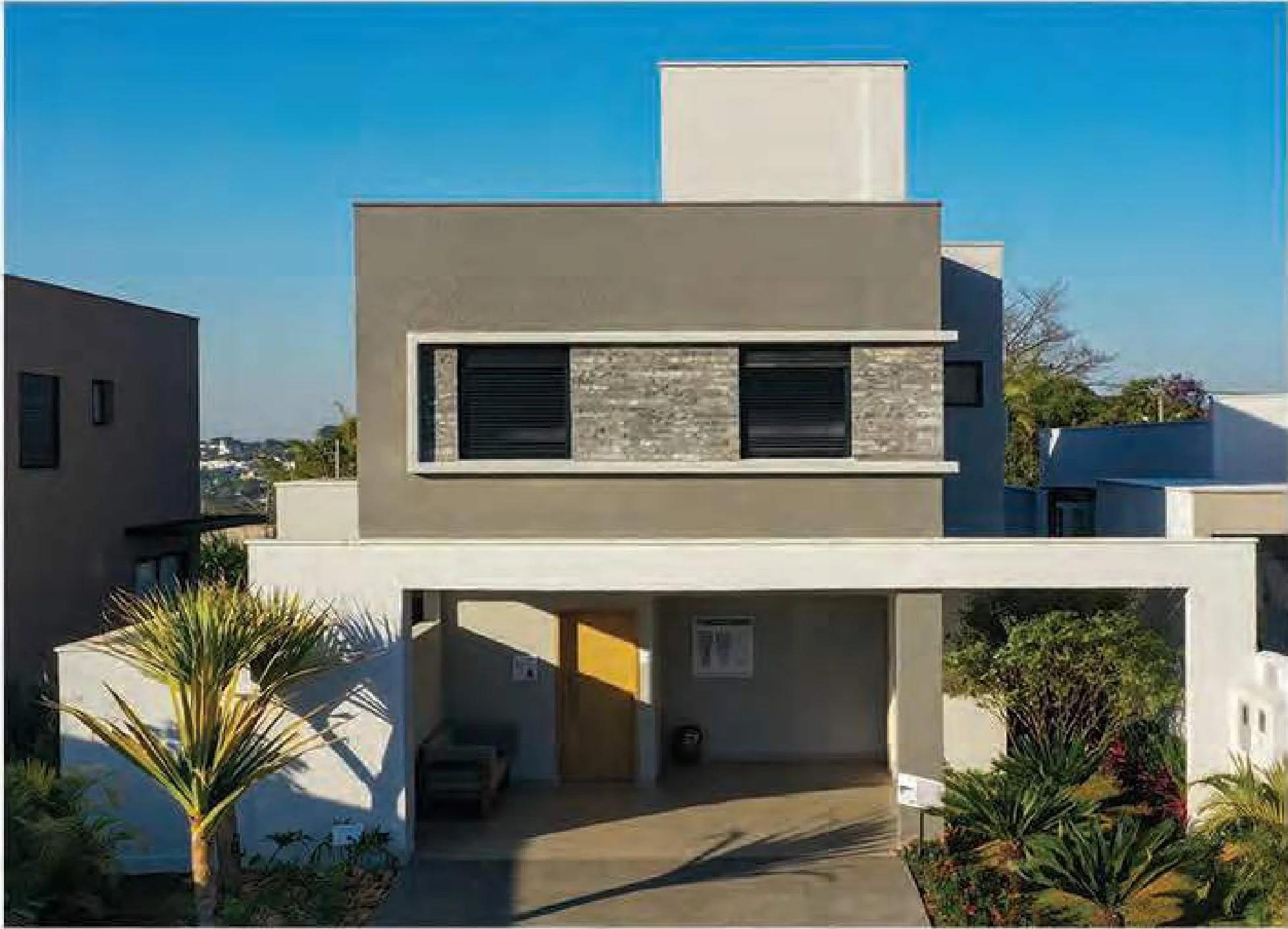 Fachada de casa duplex com detalhes em pedra natural e garagem coberta