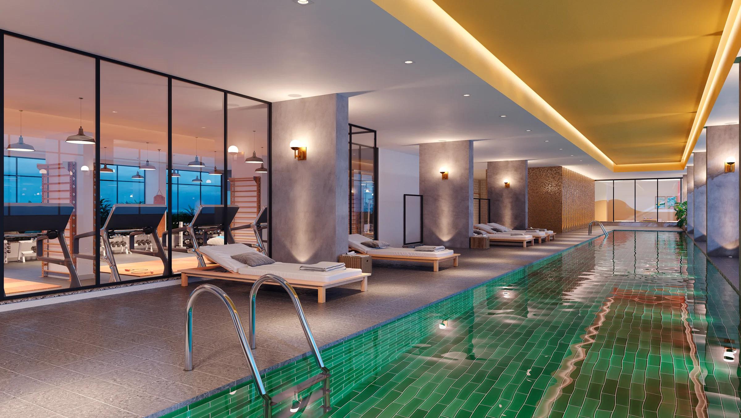 Piscina coberta com raia de 22 metros revestida em azulejos verdes e iluminação indireta