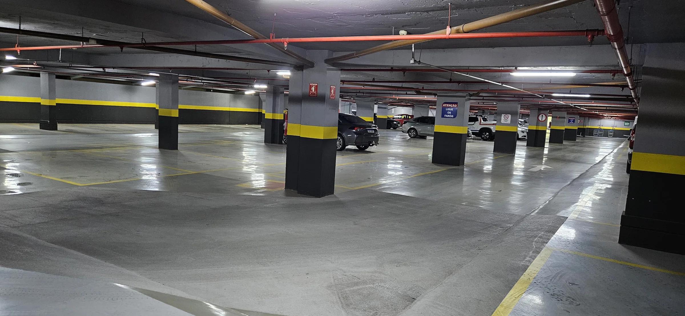 Estacionamento subterrâneo com vagas demarcadas e pilares sinalizados