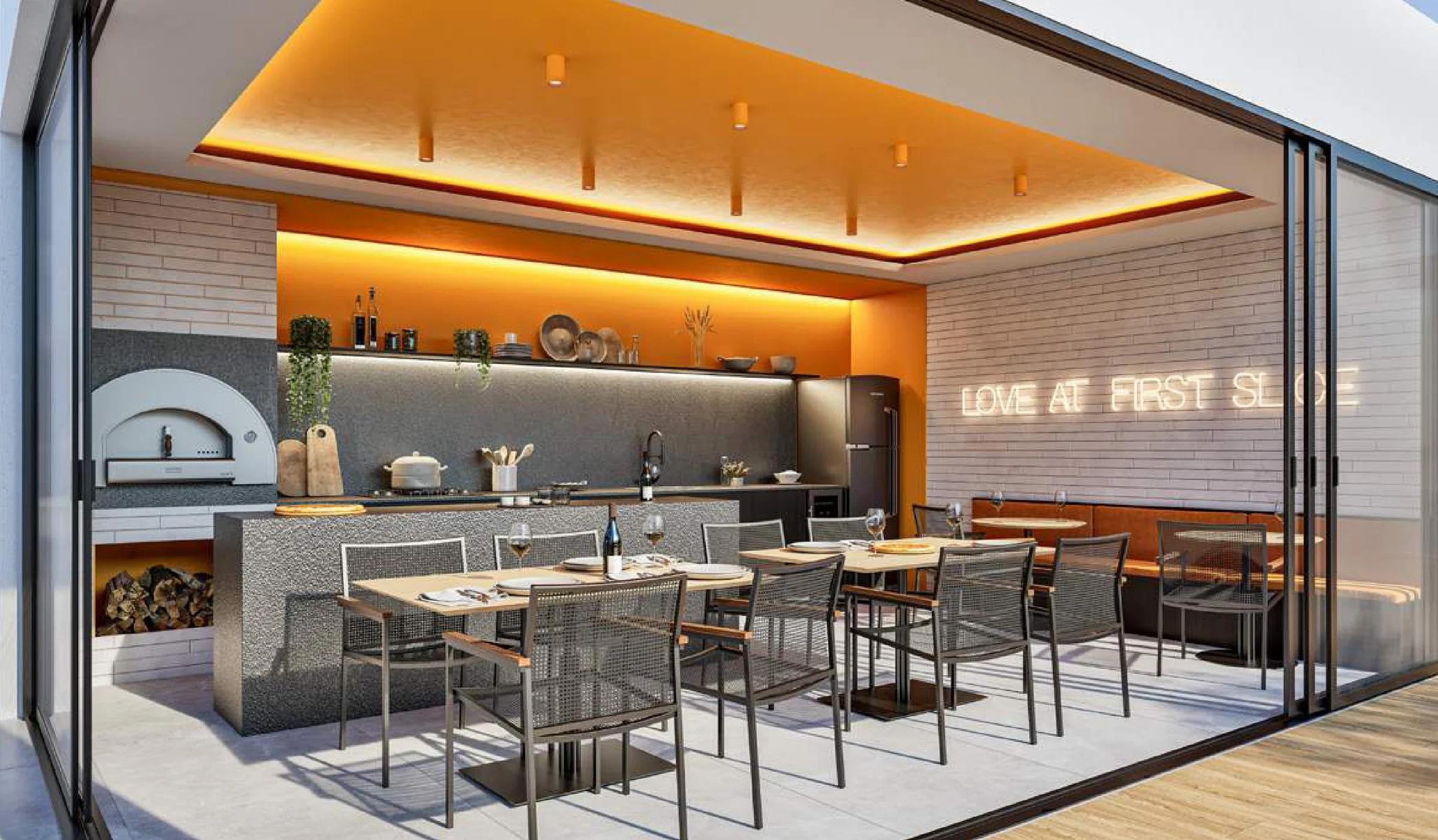 Espaço pizza gourmet com forno a lenha, bancada central e mesas de refeição