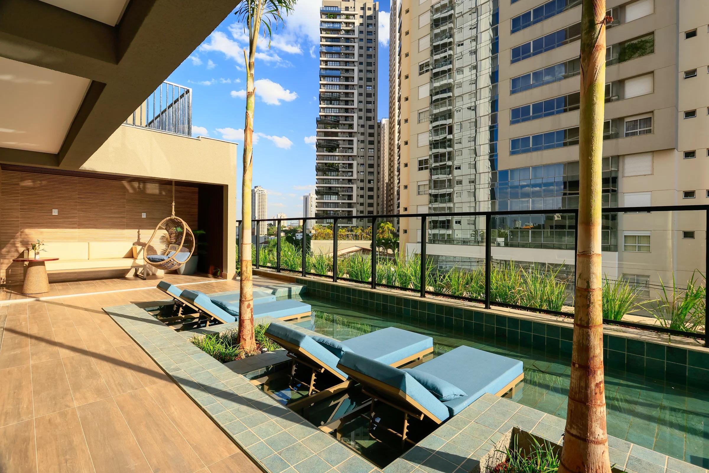 Deck molhado com espreguiçadeiras e palmeiras na área da piscina