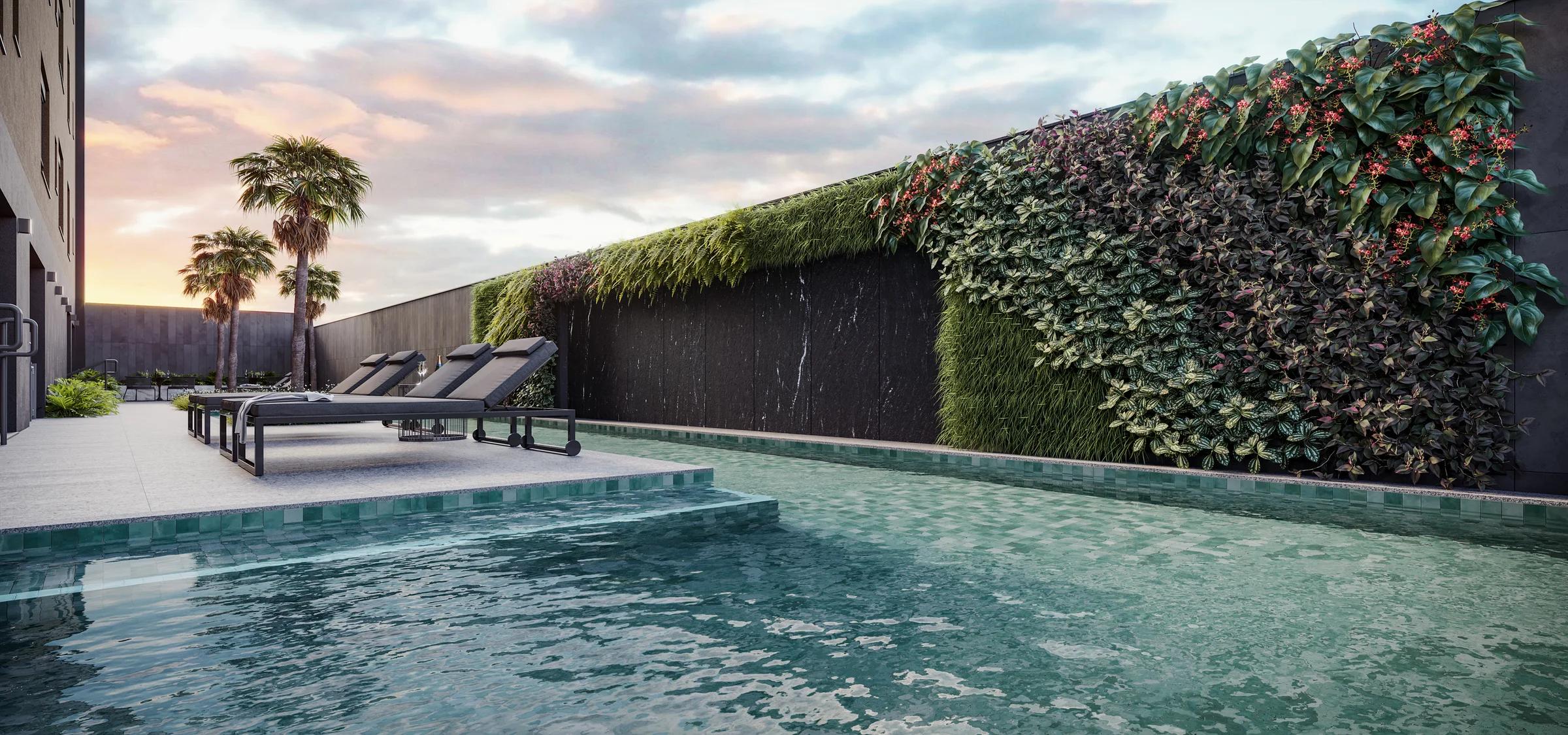 Piscina ao ar livre com parede verde, palmeiras e espreguiçadeiras