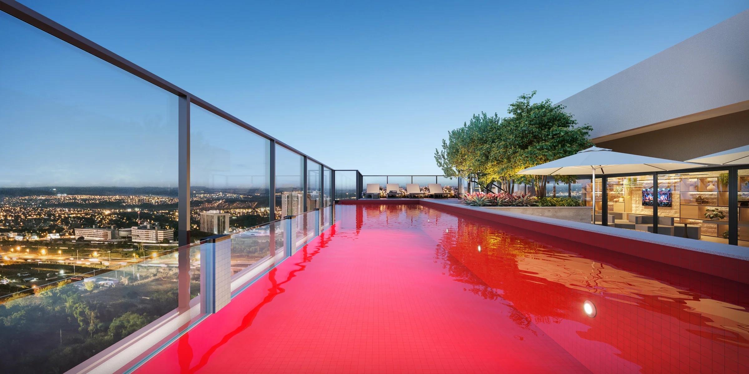 Piscina vermelha iluminada no rooftop com vista noturna para o horizonte da cidade