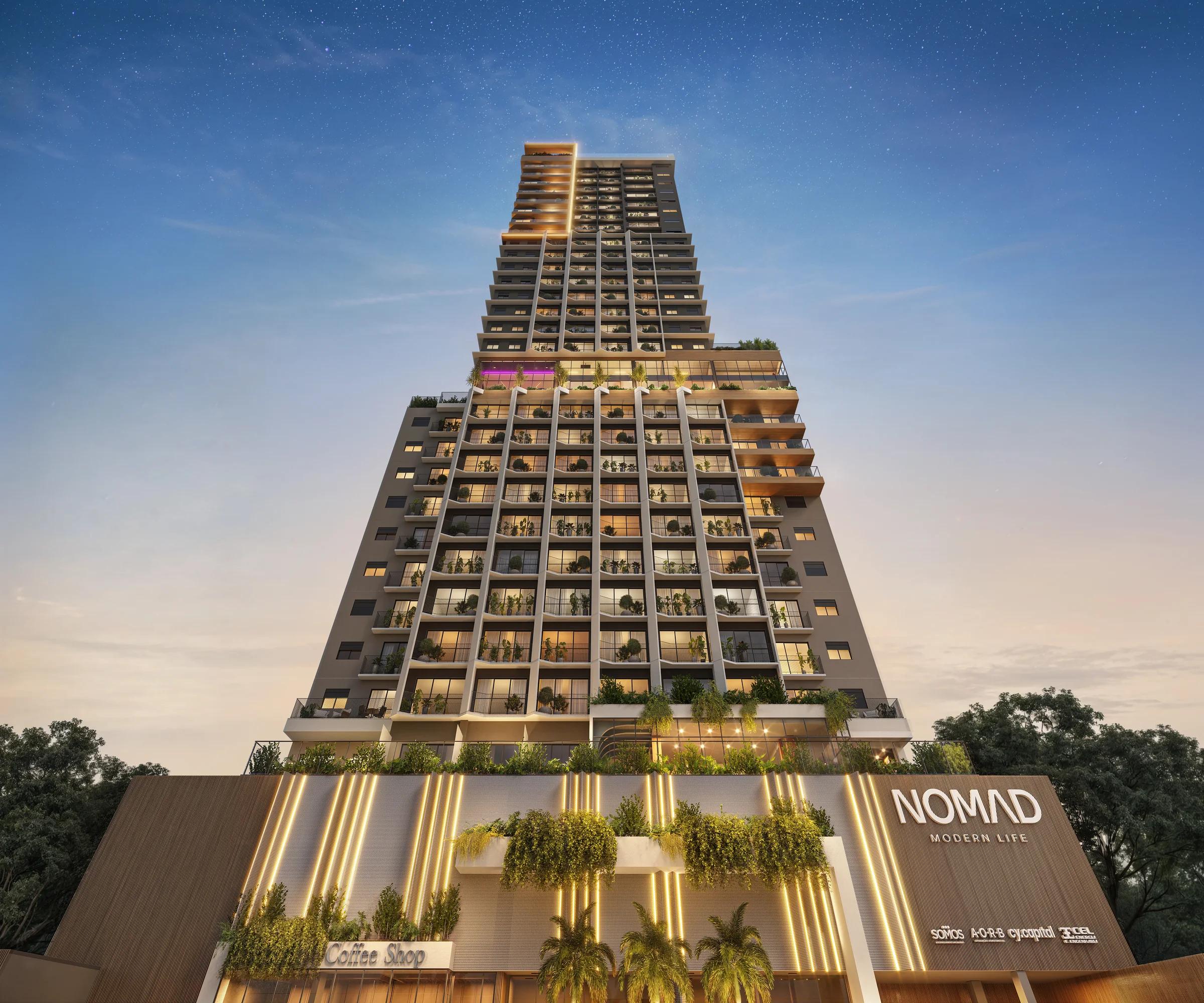 Fachada frontal do edifício Nomad Modern Life iluminada ao entardecer com vista para a base comercial e torre residencial