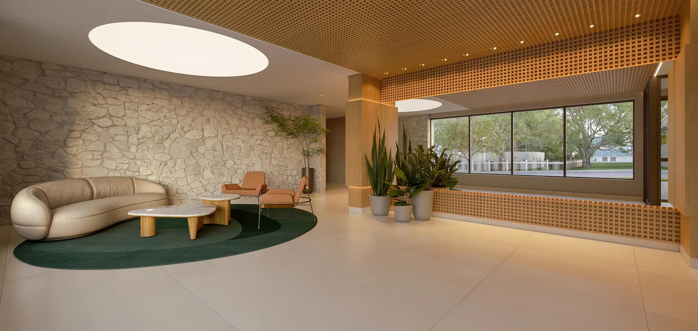 Lobby de entrada com parede em pedra natural, forro trabalhado e sofá curvo
