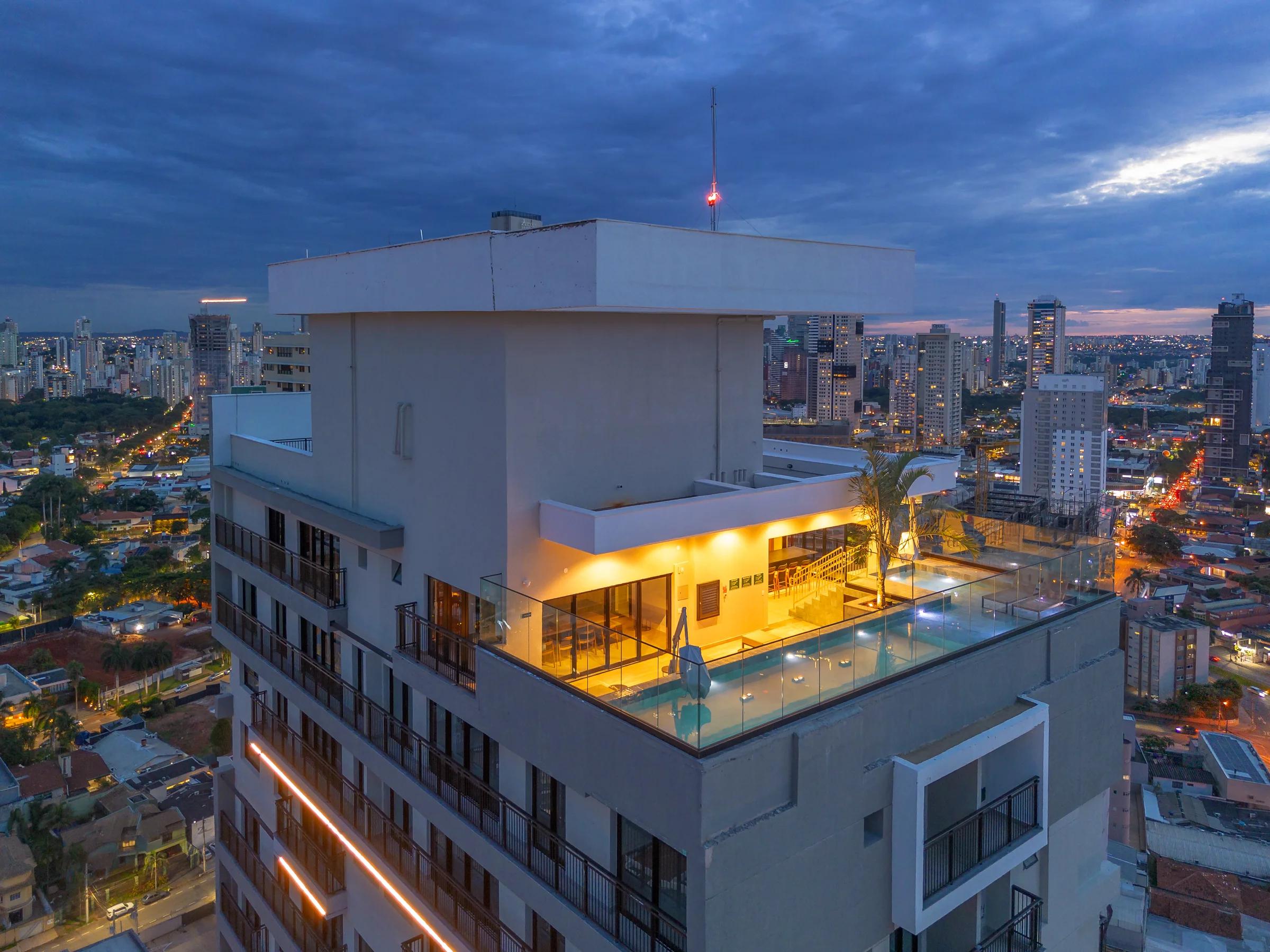 Piscina e deck no rooftop com vista panorâmica da cidade ao entardecer